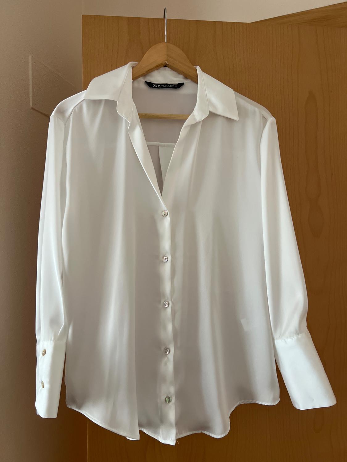 Front view of a white button-up shirt with a classic collar.