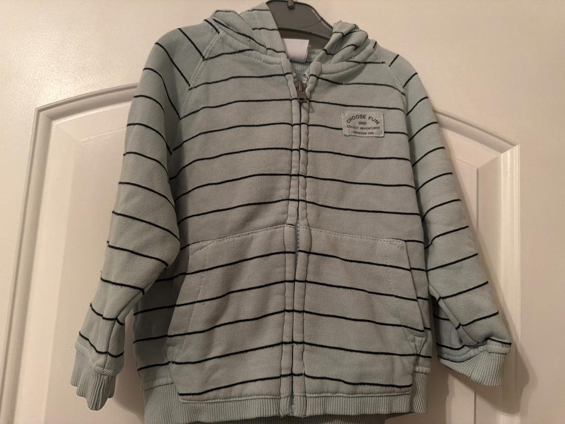 Light gray hoodie with black stripes, front zipper, and pocket. Text on chest: "CHOOSE FUN AND COLLECT ADVENTURES".
