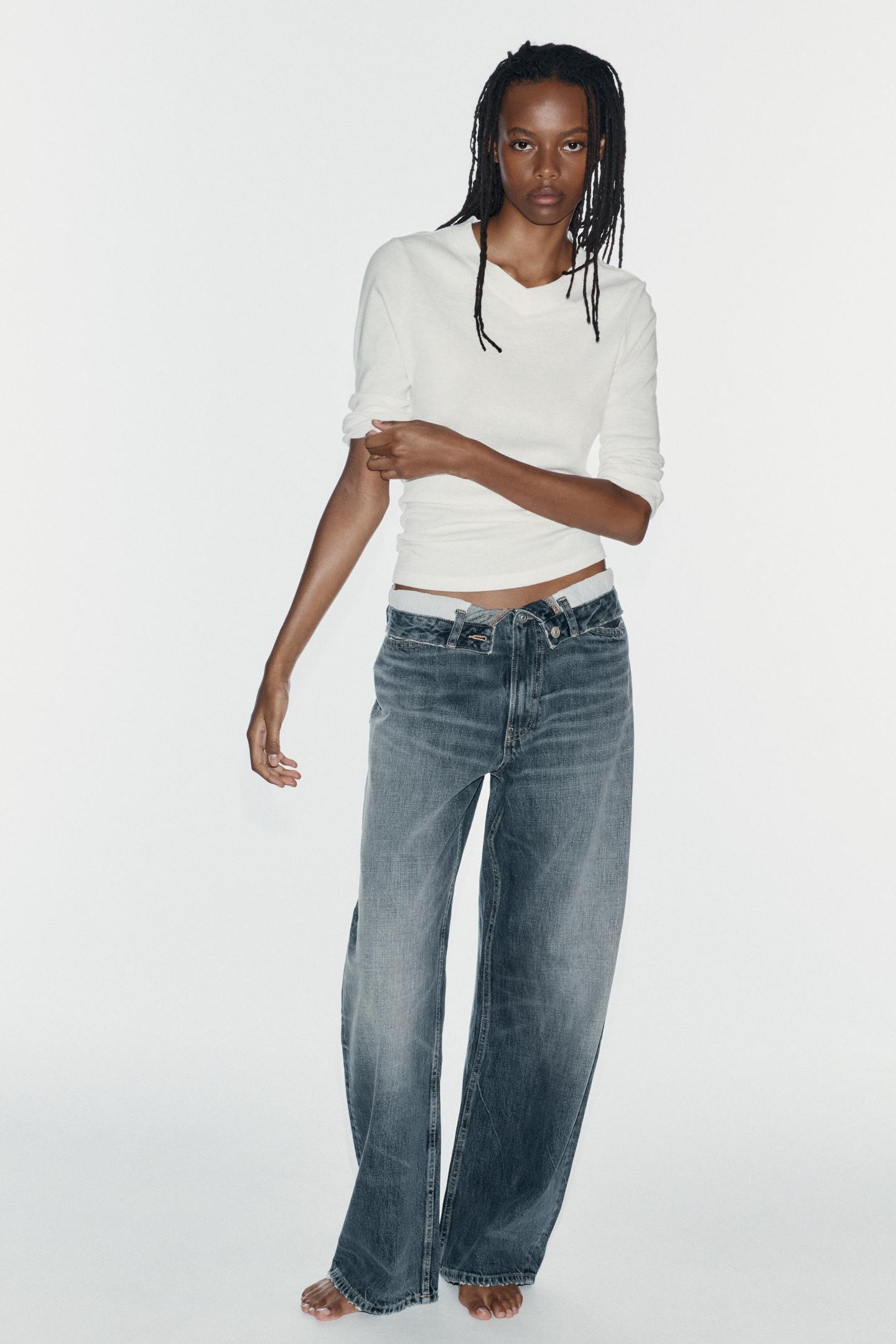 Outfit consisting of a white long-sleeve t-shirt and wide-leg blue jeans with a folded waistband and front pockets.