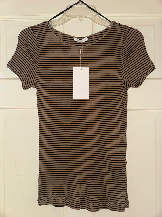 Black and brown striped t-shirt hanging on a clear hanger, with a white tag hanging in the center.