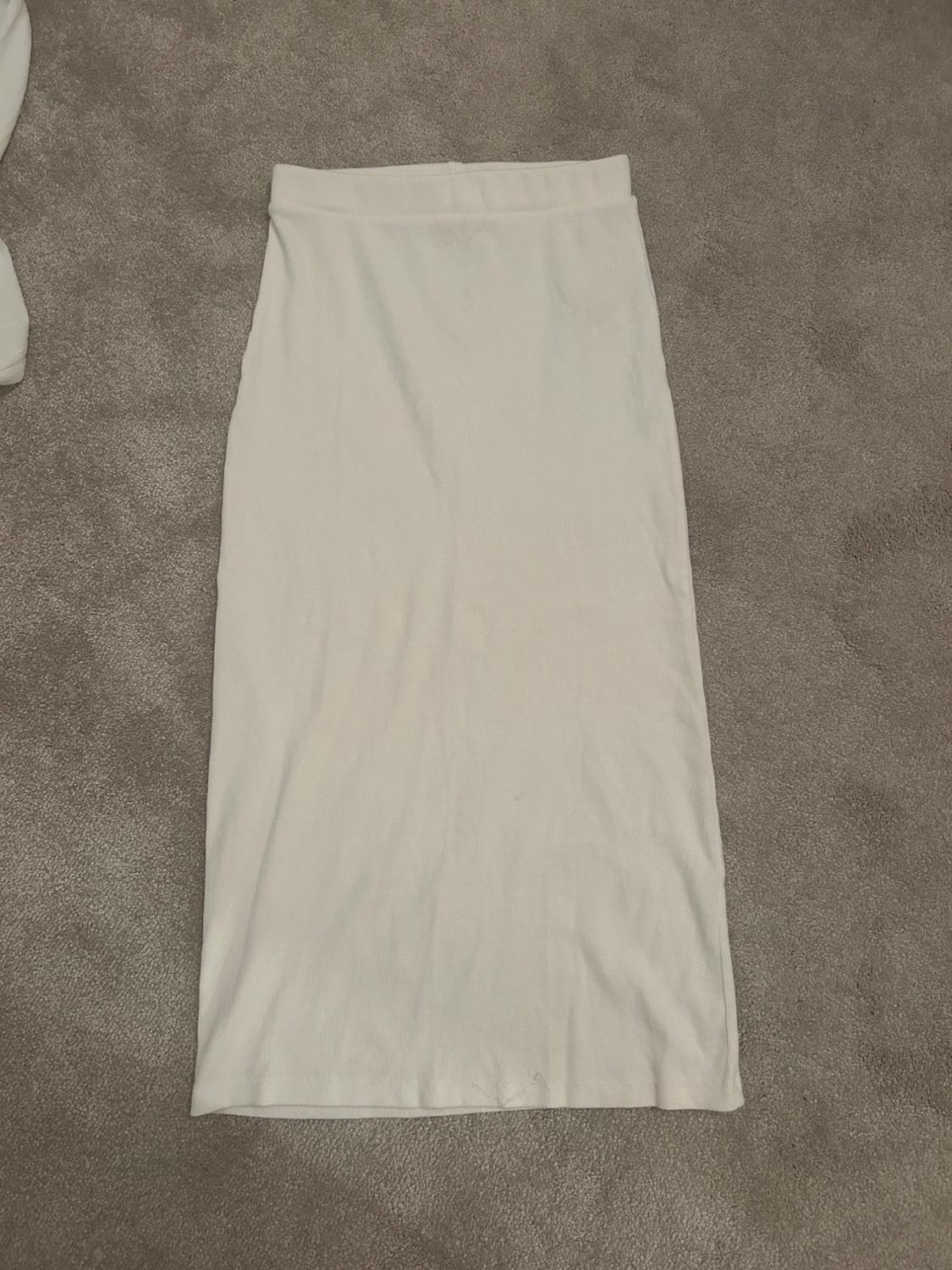 White straight-cut skirt on a grey carpet.