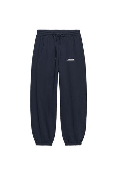 Front view of blue jogger trousers with adjustable elasticated waistband, front pockets and "California" text on the front.