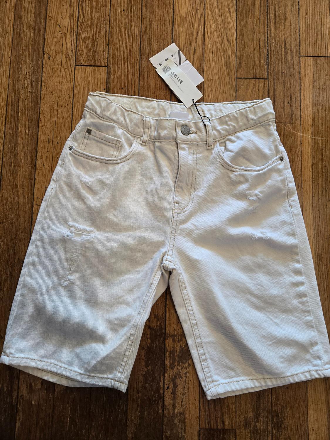 Front view of white shorts with front pockets and distressed details.