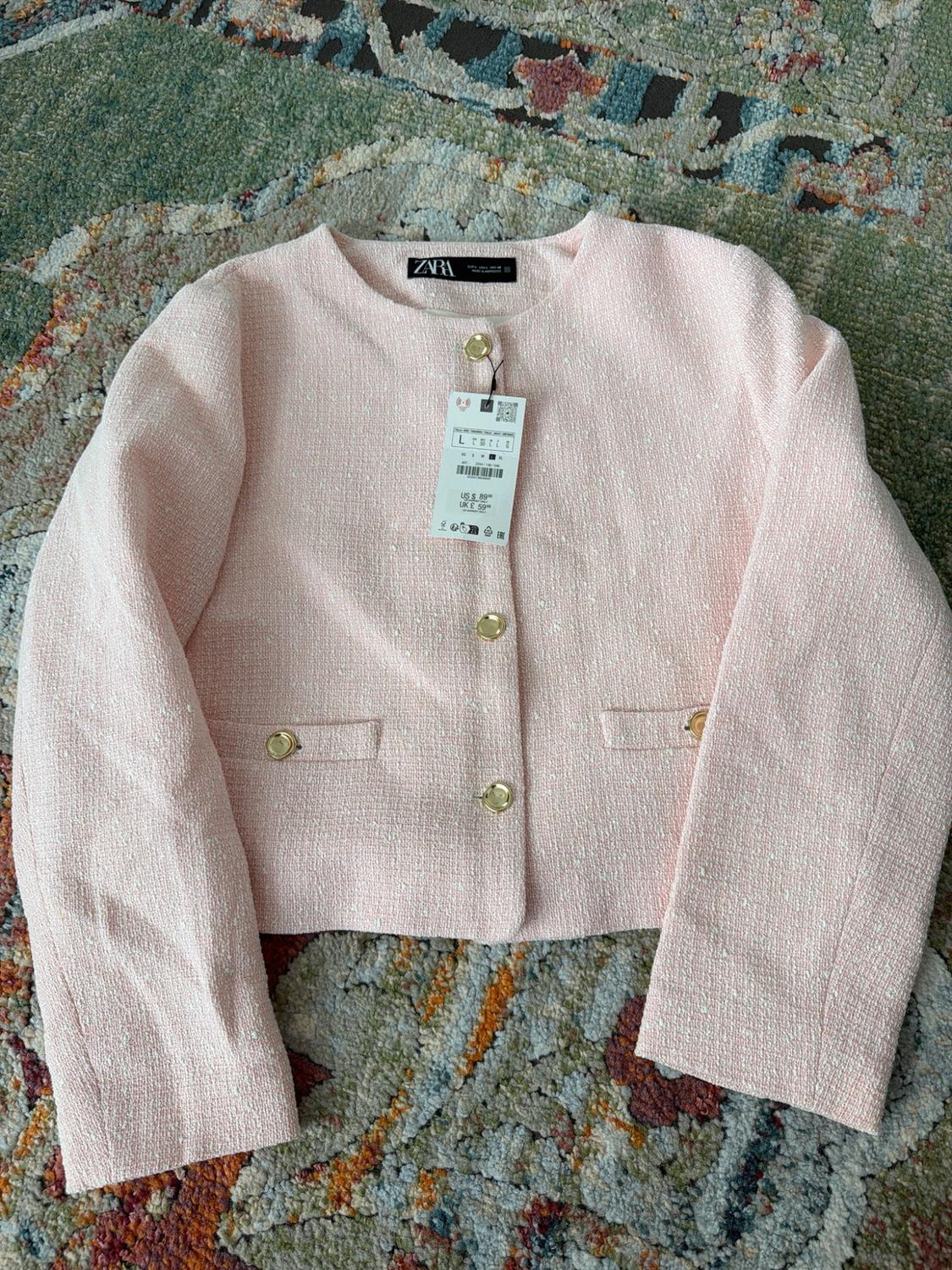 Textured pink cropped jacket with gold buttons on a rug. Text: ZARA, L, US$89.90, UK£59.99.