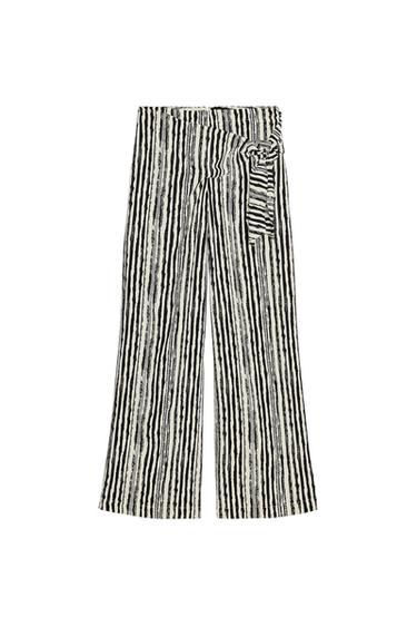Front view of wide-leg black and white striped pants with side tie belt.