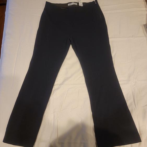 Black flared pants on a white surface, with a visible tag at the waist.