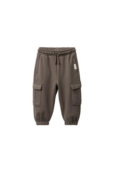 Front view of green cargo jogger trousers with elasticated waistband, adjustable drawstrings and side pockets with flaps.