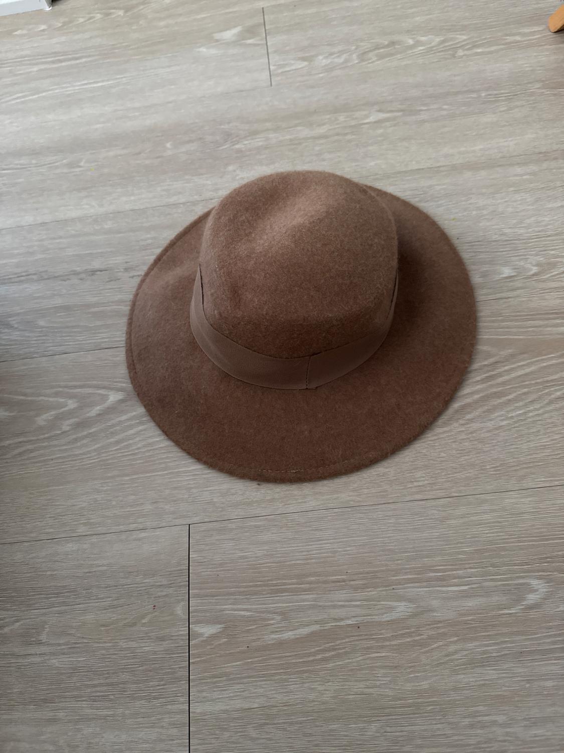 Brown wide-brimmed hat on light wooden floor. The design is simple and elegant, ideal for a casual look.