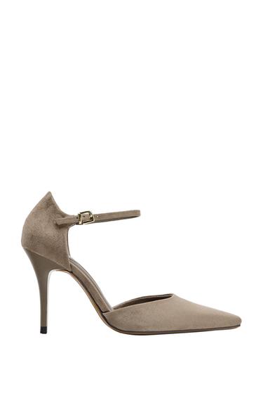 Side view of a taupe grey shoe with a slender high heel, a pointed toe, and an adjustable ankle strap with a buckle fastening.