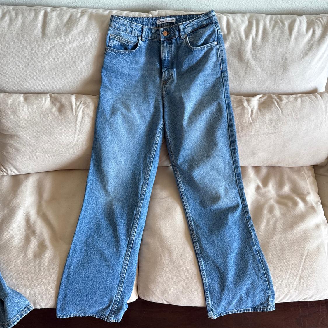Straight-cut blue jeans placed on a beige sofa. Label visible at the waist.