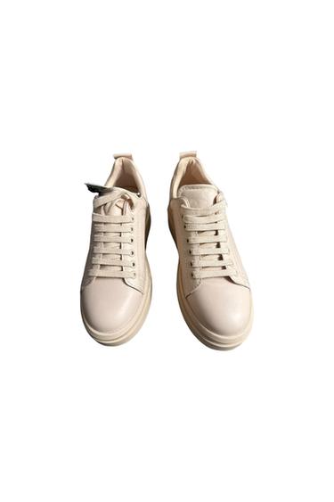 White leather lace-up sneakers, viewed from above on a white background. Simple and modern design.