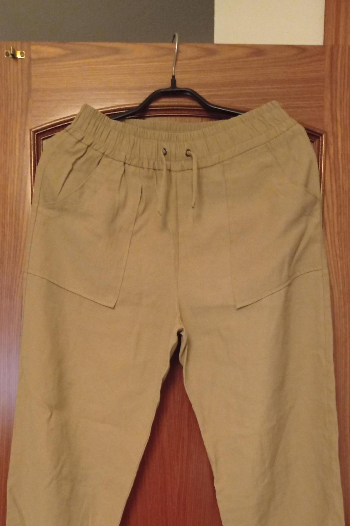 Front view of beige trousers with front pockets and an elasticated waist.
