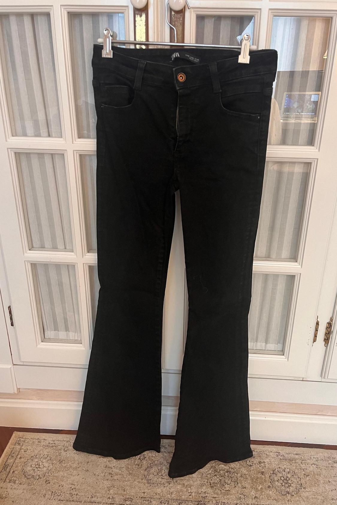 Front view of black flared trousers with front pockets and a visible button.