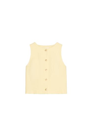 Front view of a beige sleeveless vest with center button closure.