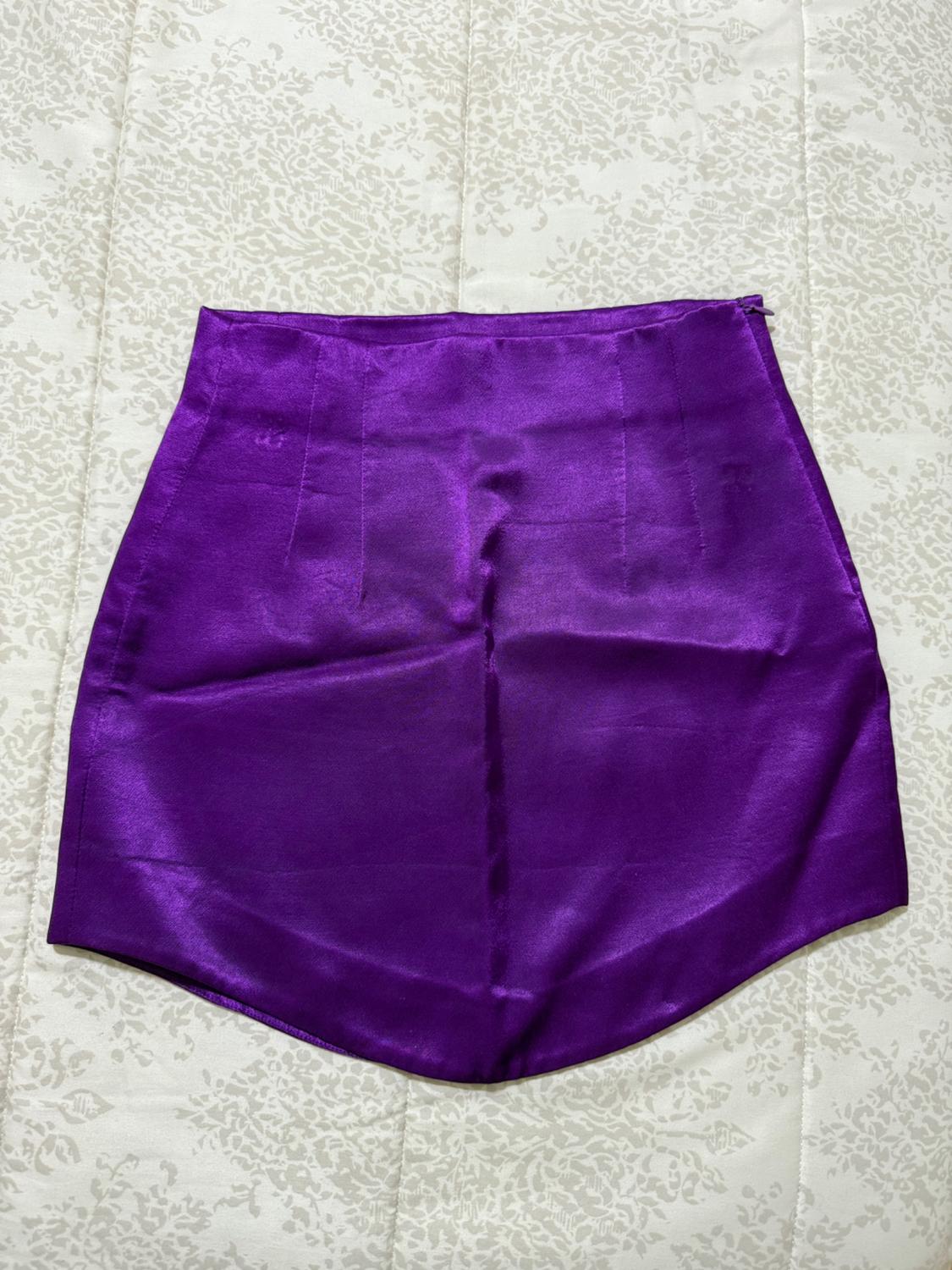 Purple satin mini skirt on a white fabric background with an embossed floral design.