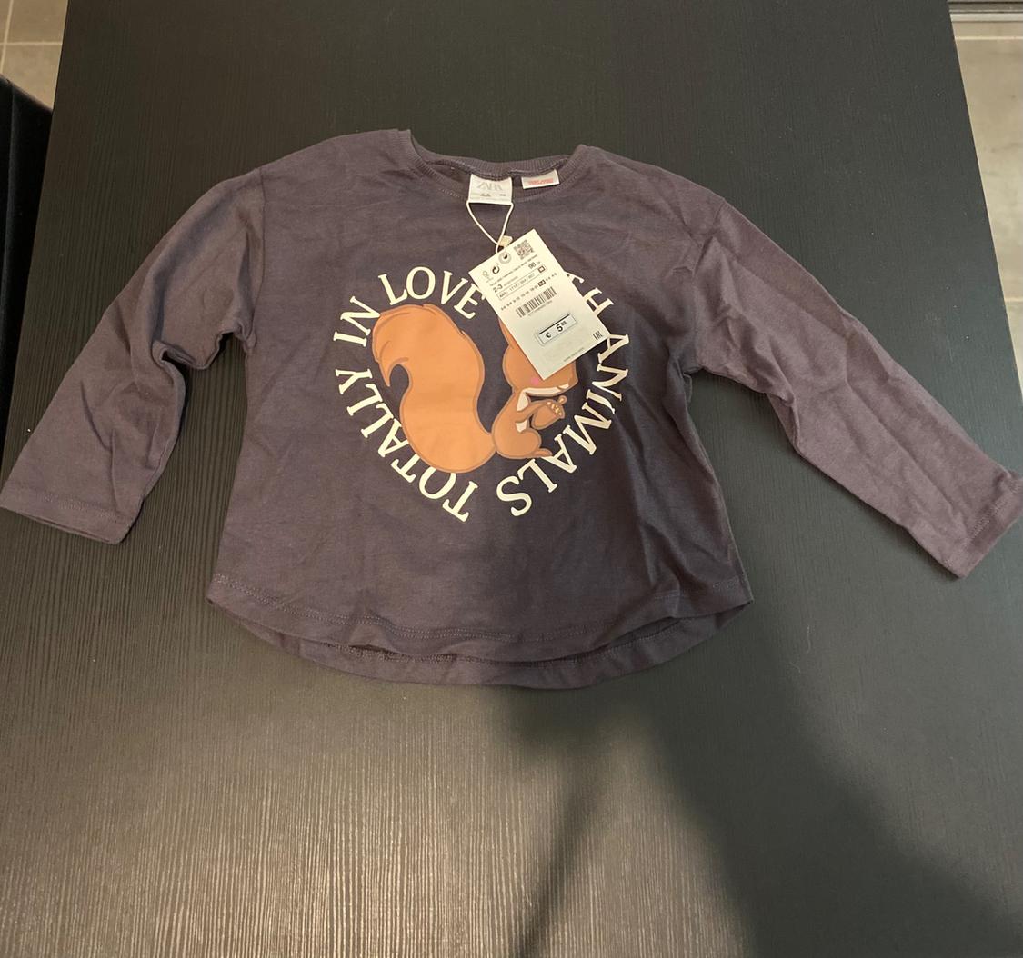 Μακρυμάνικο γκρι T-shirt με σχέδιο σκίουρου και κείμενο "TOTALLY IN LOVE WITH ANIMALS" πάνω σε μαύρο τραπέζι, με κρεμαστές ετικέτες.