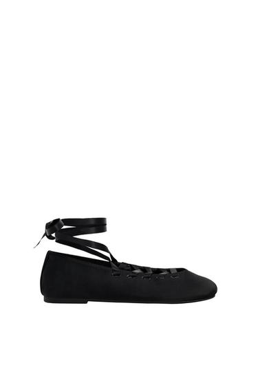Black ballerina with long ankle-tie ribbons, side view on a white background. Elegant and minimalist design.