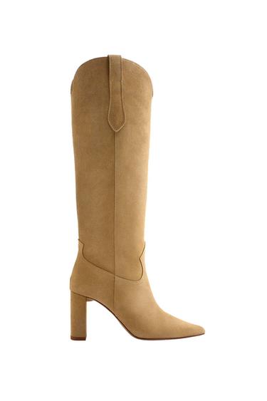 Chunky heeled knee-high boot in beige, with a minimalist design and pointed toe, on a white background.