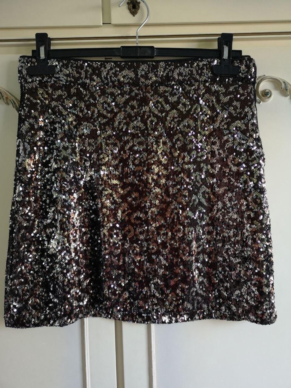 Animal print sequin mini skirt, hanging on a black hanger in front of classic white wardrobe doors.