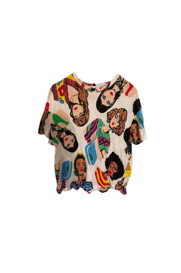 Front view of a t-shirt with a colorful faces print and a round neck.