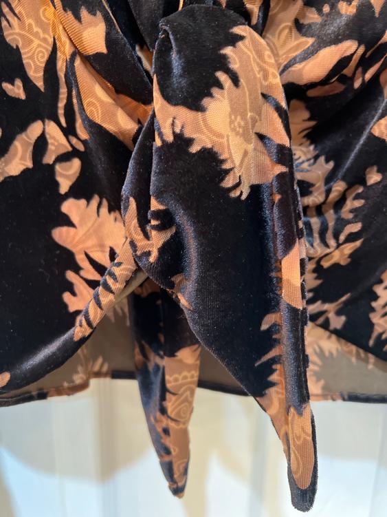 Close-up of a fabric bow with a floral print in black and brown tones, showing soft texture and intricate details.
