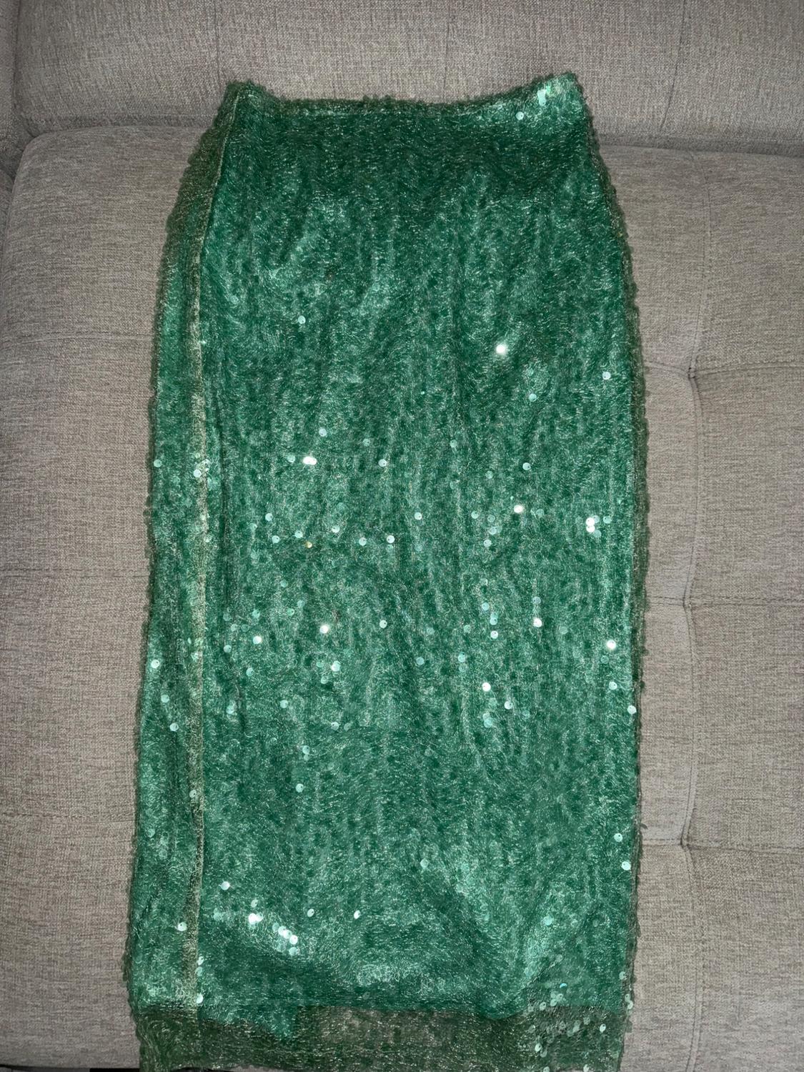 Green skirt with shiny sequins on a light gray sofa. The fluffy texture and shine stand out in the image.