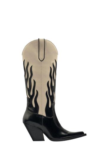 Side view of a black cowboy boot with a beige flame design and a high heel.