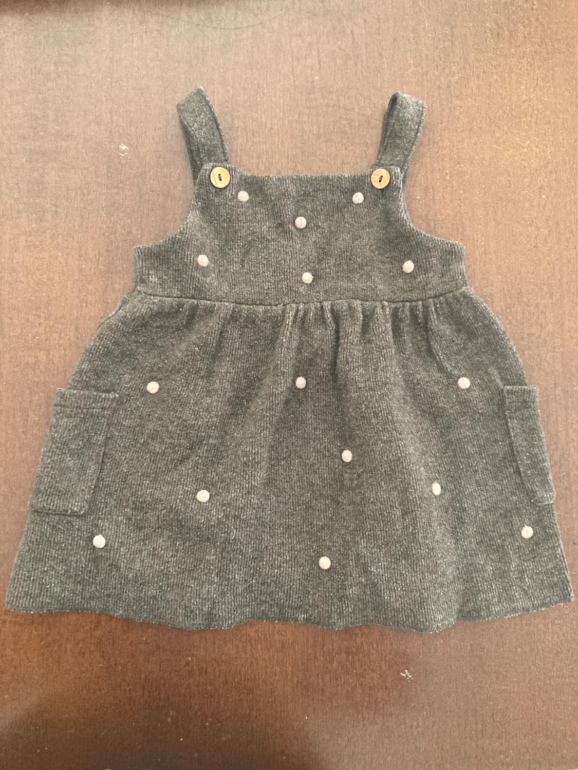 Grey strappy dress with wooden buttons and small white circular embellishments, on a brown wooden background.