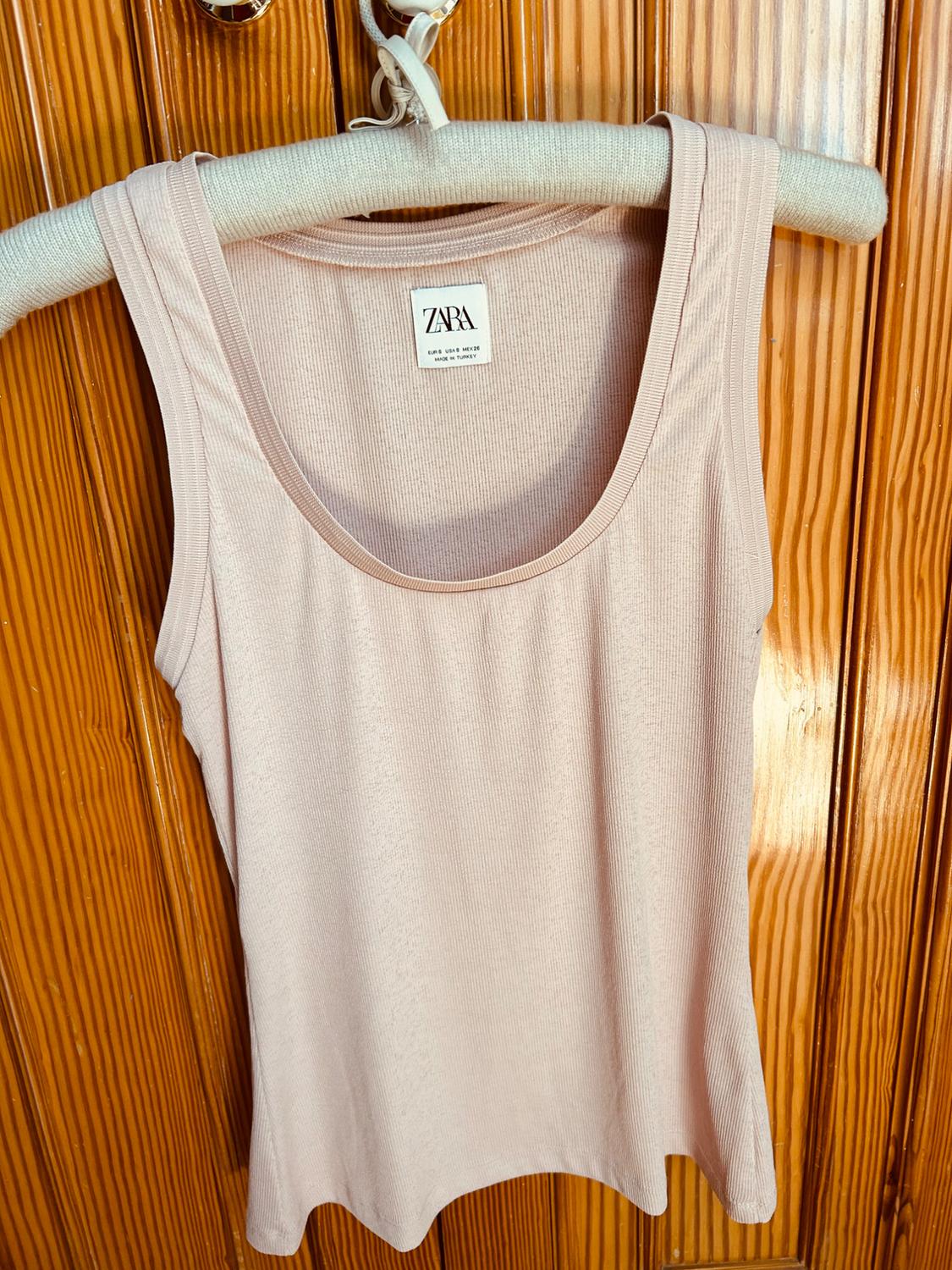 Front view of a light beige sleeveless t-shirt with a round neckline.