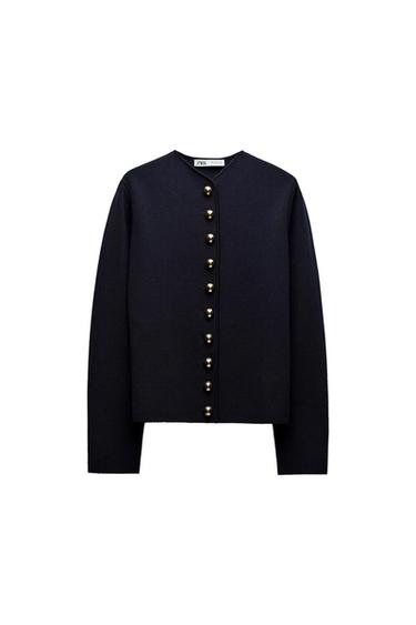 Long-sleeved black jacket with gold buttons down the front. "Zara" label visible on the neck. White background.