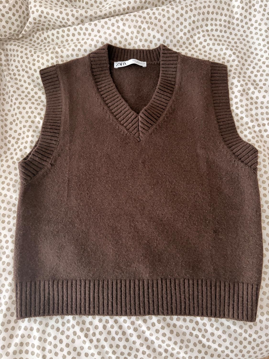 Brown knitted V-neck gilet over a polka dot fabric. Visible label with text "ZARA".