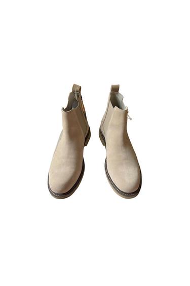 Pair of beige suede ankle boots with elastic side panels and a rear pull tab against a white background.