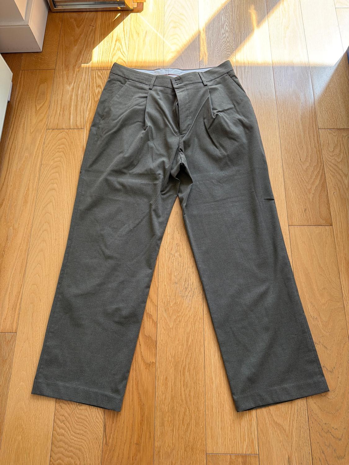 Straight-cut gray pants on light wood flooring, illuminated by natural light from a nearby window.