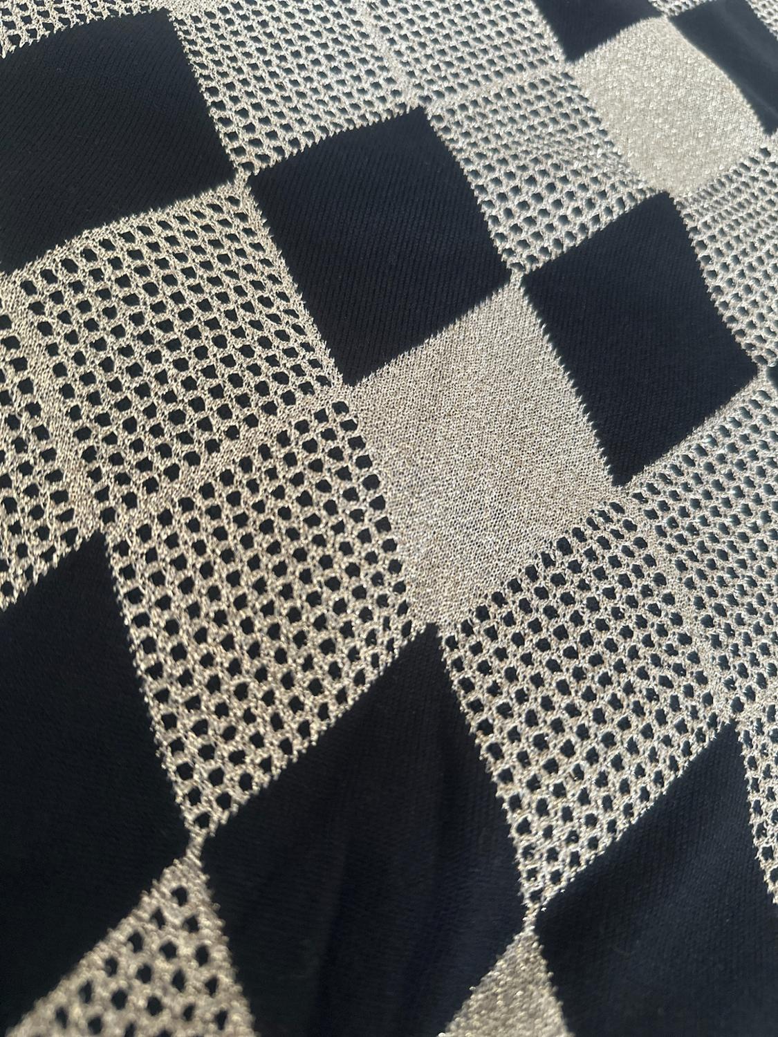 Fabric detail with a black and bright light-toned check pattern. Alternates solid knit sections with openwork mesh areas.