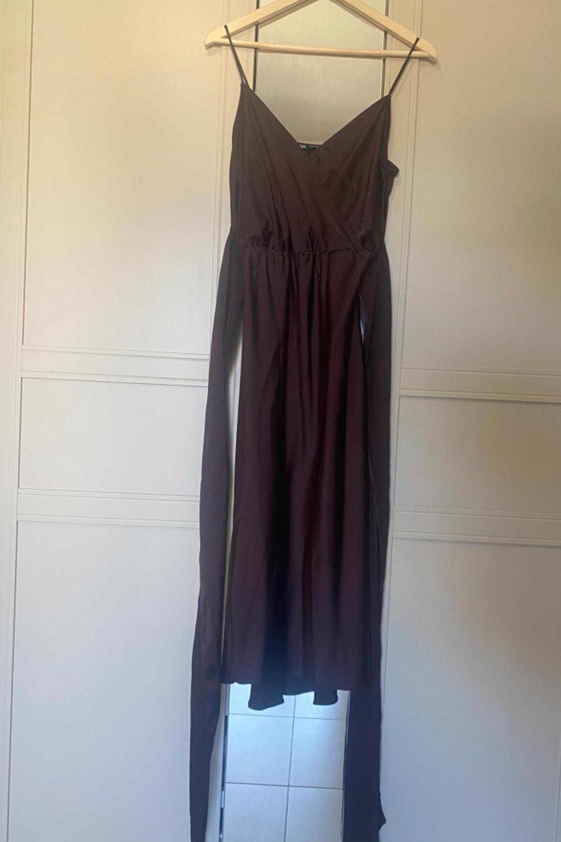 Front view of a dark brown dress with thin straps and a crossover neckline.