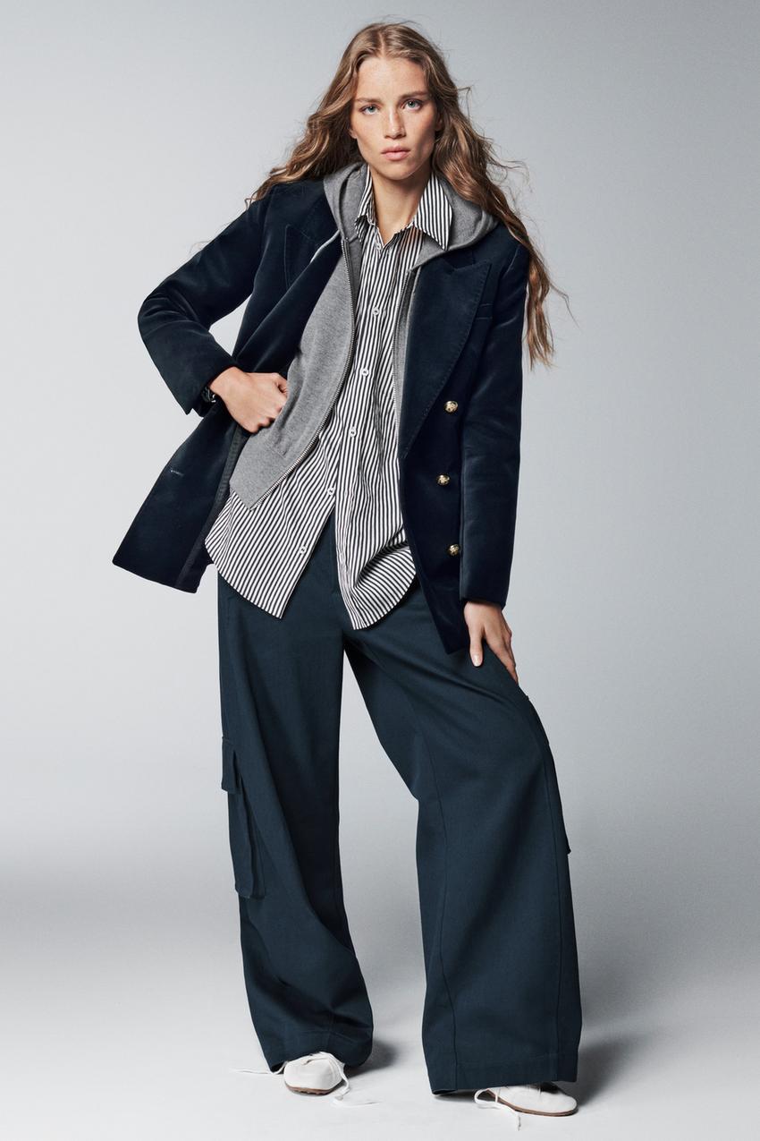 Navy blazer with gold buttons, black and white striped shirt, gray sweatshirt, and dark blue wide-leg pants.