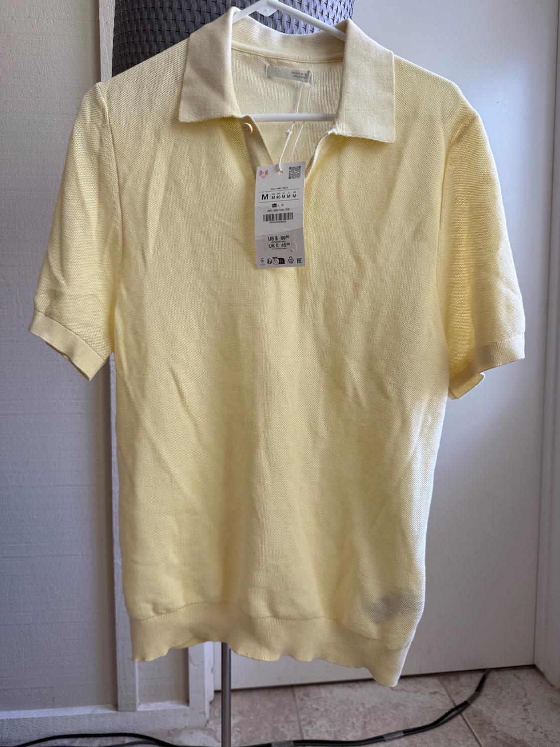 Short-sleeved yellow polo shirt hanging on a hanger. Label with text: M 40 M M M, US $69.90, UK £45.99.