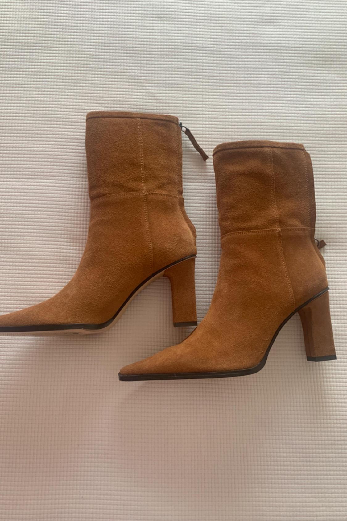 Side view of brown high-heeled boots with a pointed toe and a back zip.