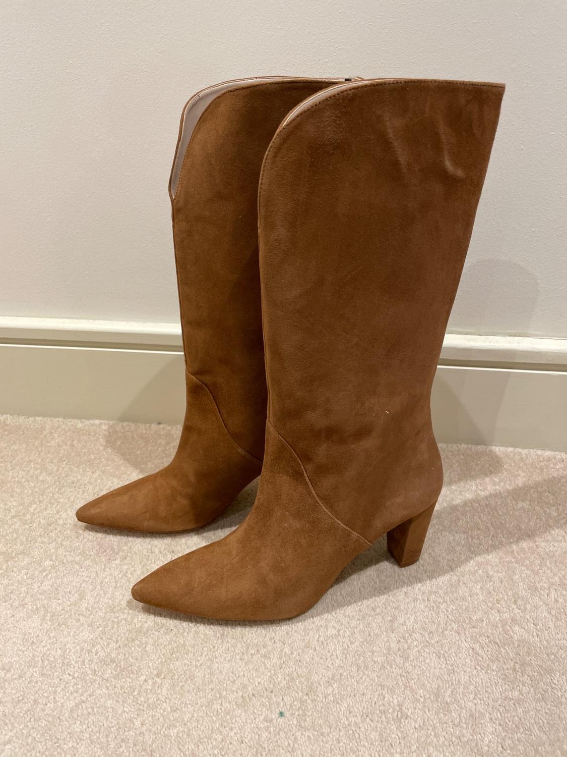 Side view of brown tall boots with a chunky heel.