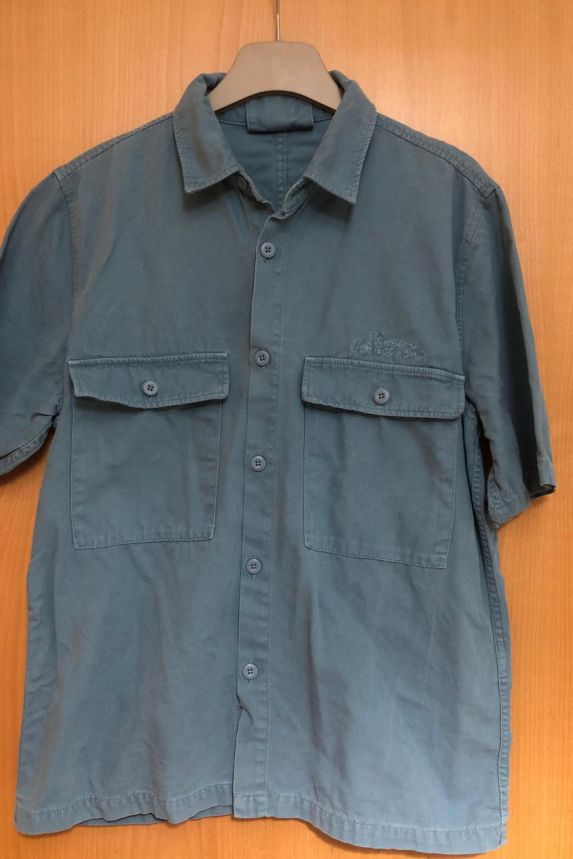 Front view of blue shirt with front flap pockets and full button-through.