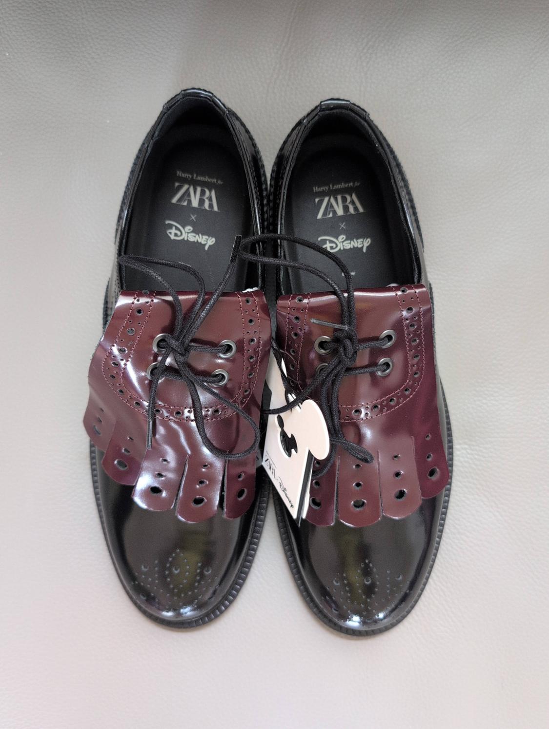 Shiny black shoes with burgundy detail and laces. Text: Harry Lambert for ZARA x Disney.
