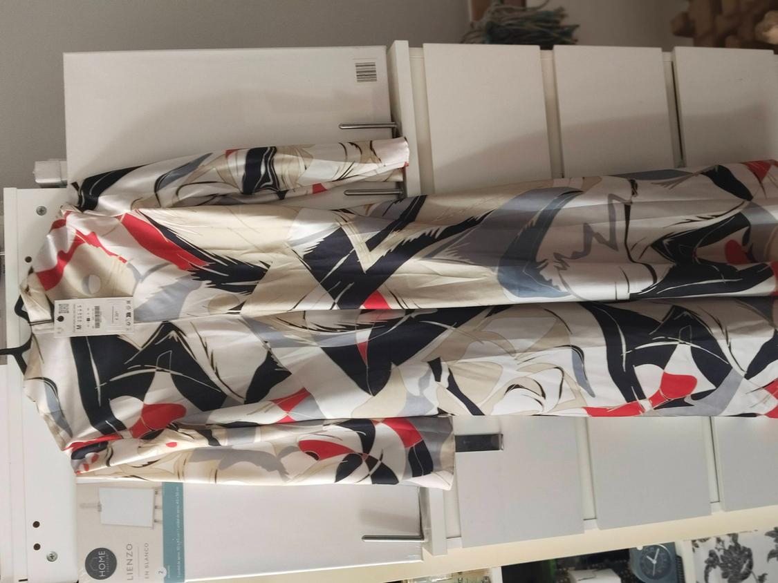 Long-sleeved dress with beige, black, and red abstract print on a white piece of furniture. Text: HOME BLANK CANVAS.