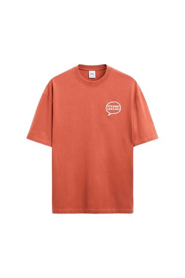 Front view of an orange t-shirt with the text 'IT'S FINE! LET'S GO!' on the chest.