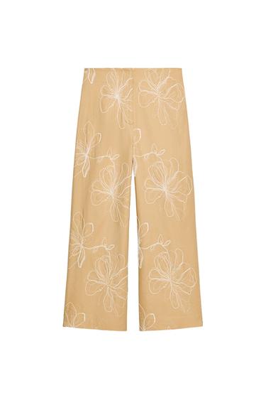 Front view of beige trousers with white floral print.