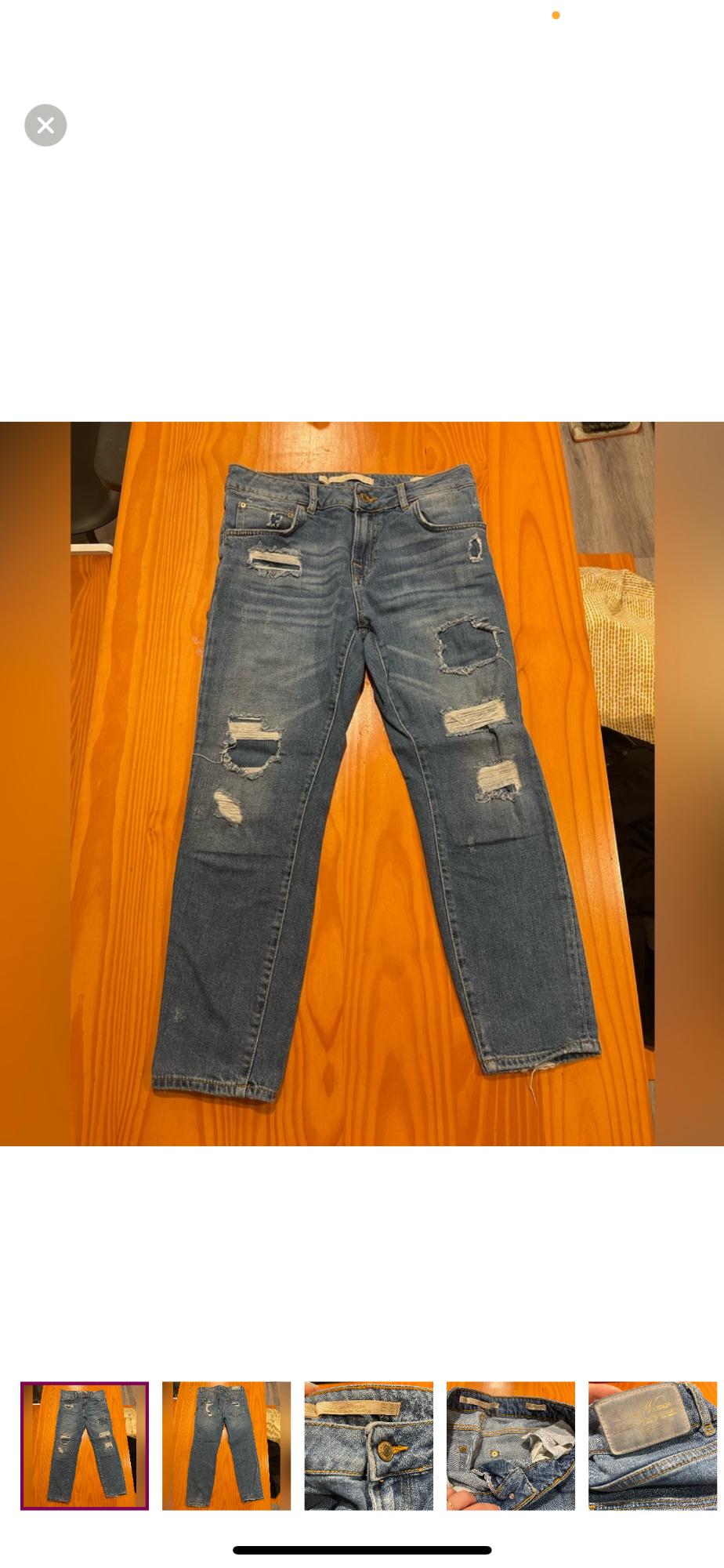 Front view of blue jeans with rips and side pockets.