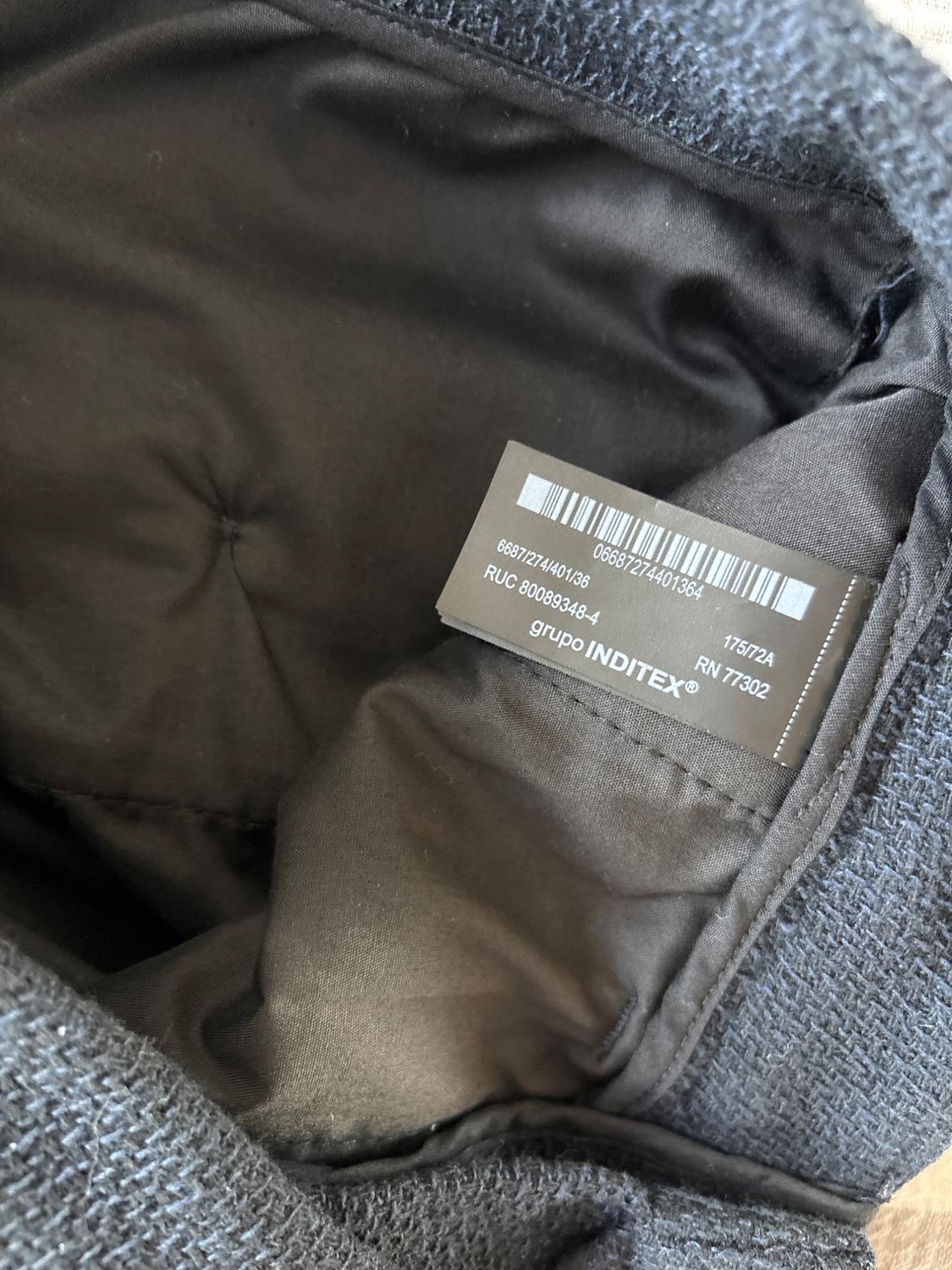 Close-up of the inside of a black coat with a visible 'GRUPO INDITEX' label.
