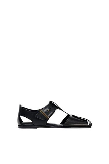 Side view of a black sandal with buckle fastening and side cut-outs.