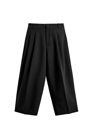 Front view of black wide fit trousers with front pleats, side and jetted back pockets, zip and button fastening.
