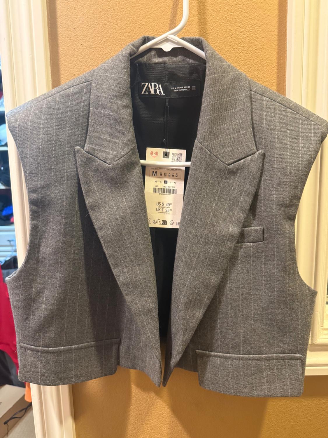 Gray vest with vertical stripes hanging on a white hanger. Visible tag with the text "ZARA" and size "M".