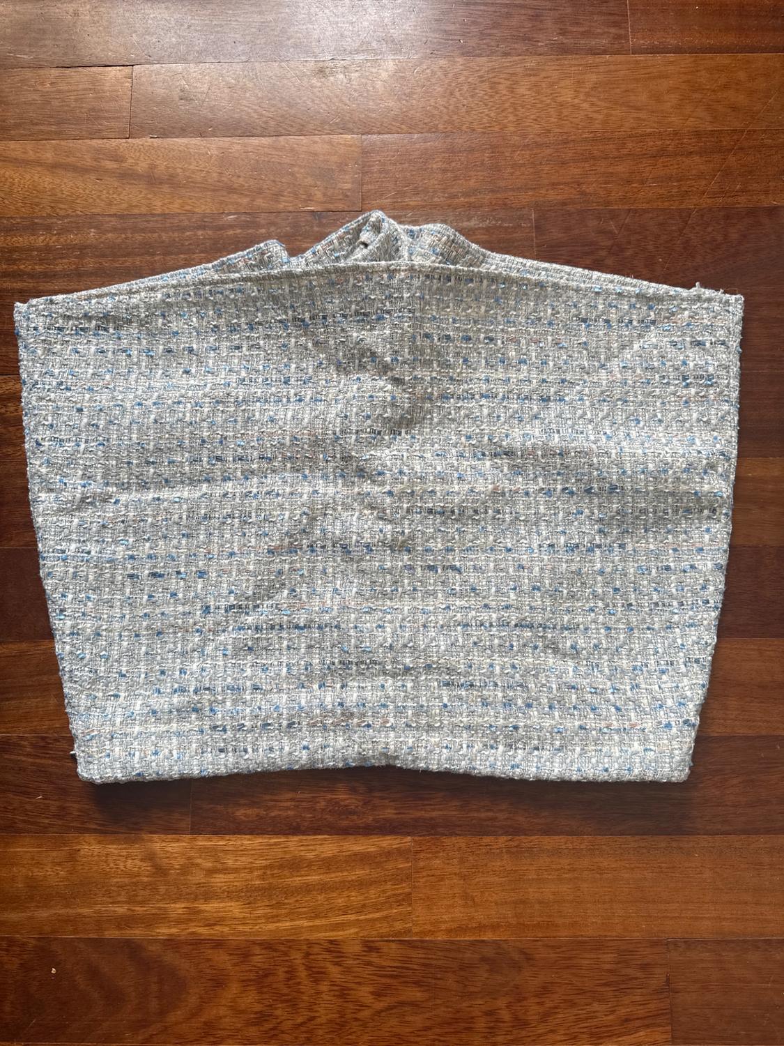 Textured grey fabric with a small checkered pattern on a brown wooden floor.